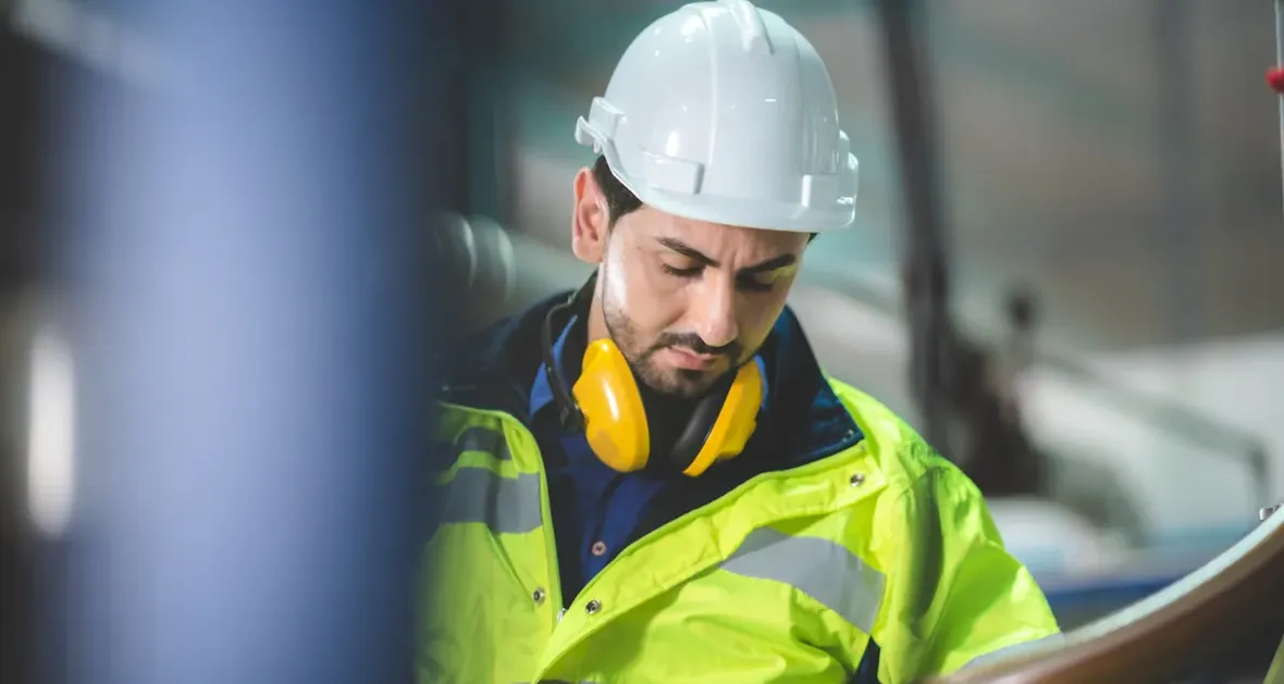 Profissional de capacete trabalhando em máquina industrial